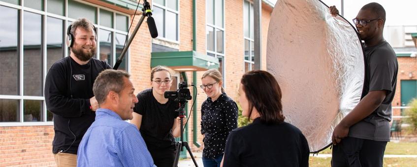 A group of students using filming equipment for an interview video.